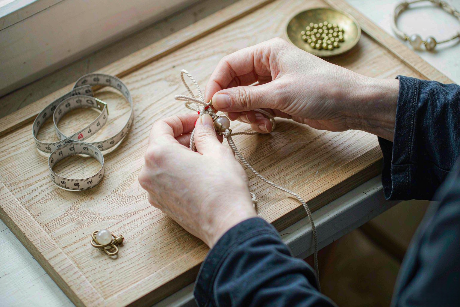 handwoven bracelet in cream cord knotted on a wooden workboard — Handwoven Jewelry by TibetanTwist